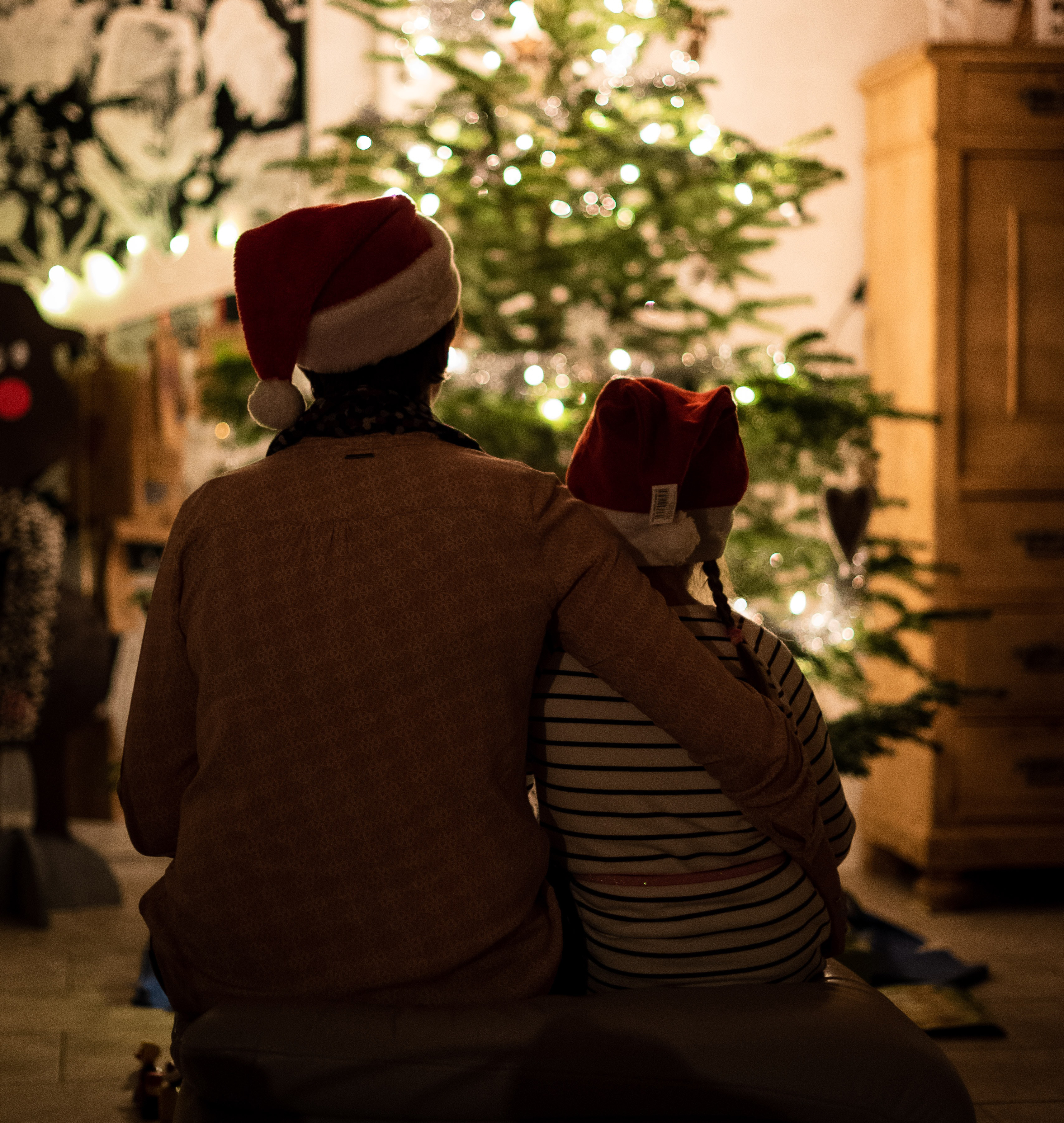 parent and child sat in front of a xmas tree