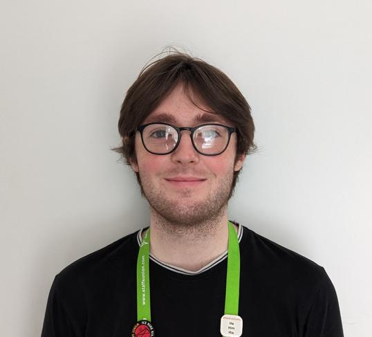 Josh Barnett, Student Voice Coordinator, smiling in front of a white background.